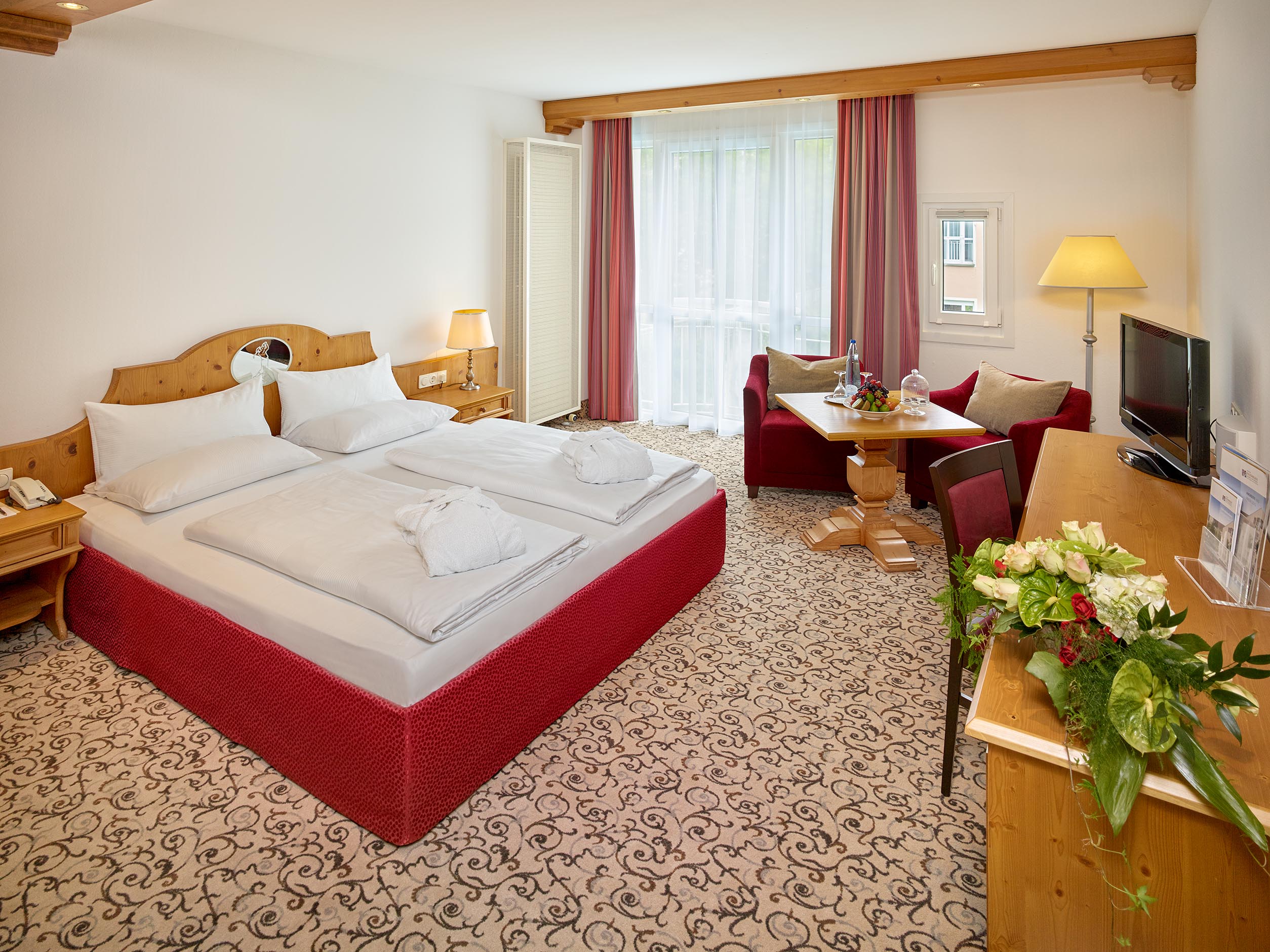 Helles Hotelzimmer mit Doppelbett, gemütlichem Sitzbereich und Tisch, ideal für einen komfortablen Aufenthalt.