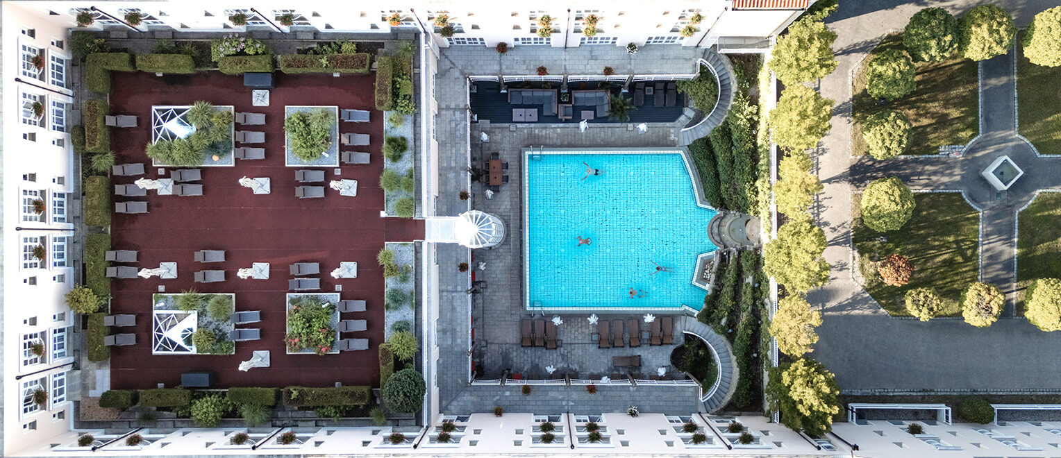Luftaufnahme des Hotelkomplexes mit einem Pool und einem gepflegten Gartenbereich.