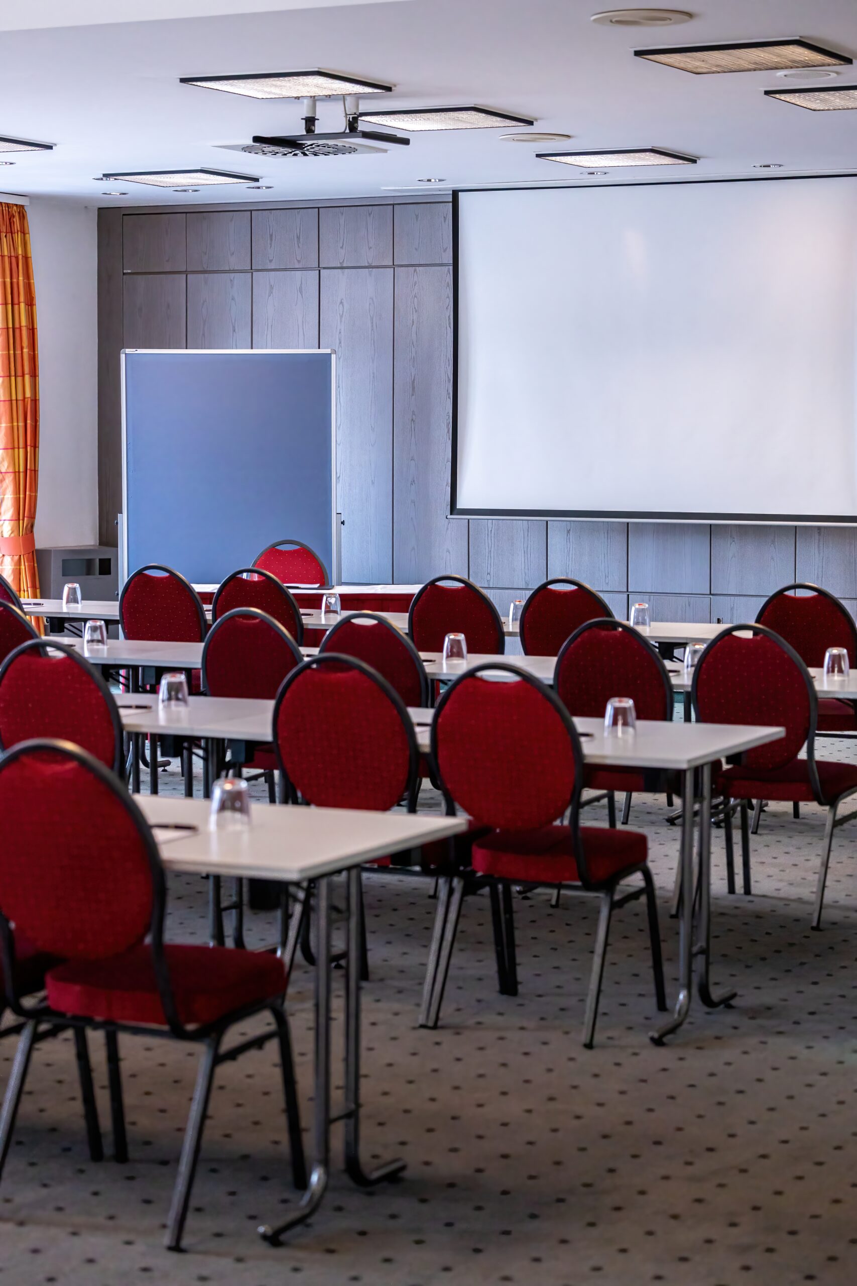 Leerer Konferenzraum mit Flipchart und Präsentationsfläche, vorbereitet für eine Tagung oder Besprechung